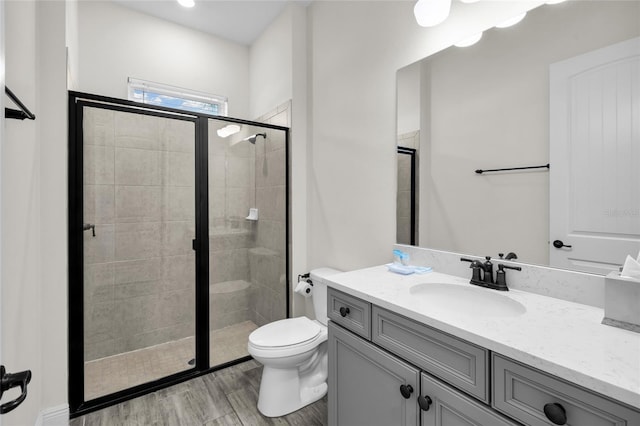 bathroom with toilet, hardwood / wood-style floors, vanity, and walk in shower