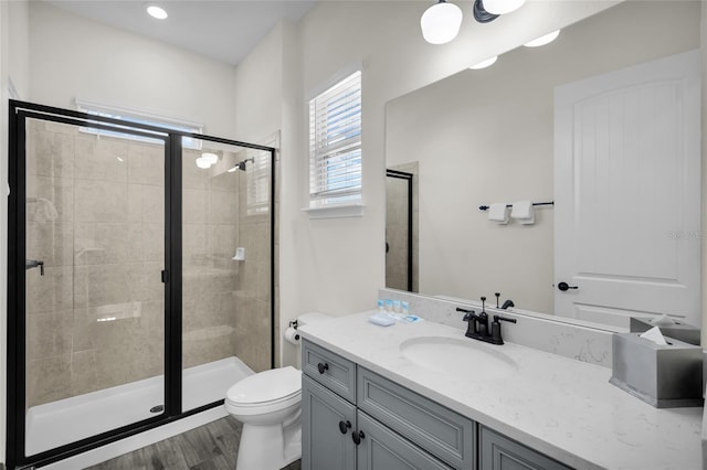 bathroom with vanity, toilet, wood-type flooring, and a shower with door