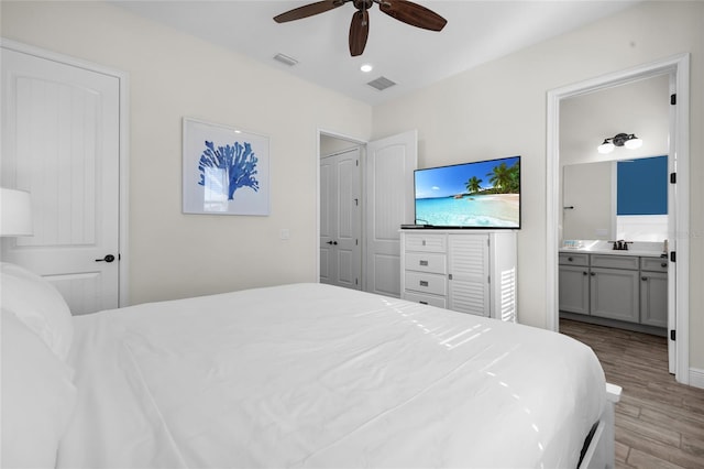 bedroom with connected bathroom, ceiling fan, light hardwood / wood-style flooring, and sink