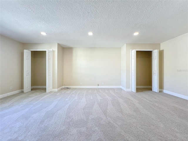 empty room with light carpet and a textured ceiling