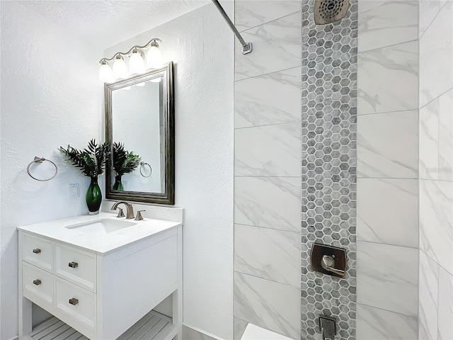 bathroom featuring a tile shower, vanity, and a textured ceiling