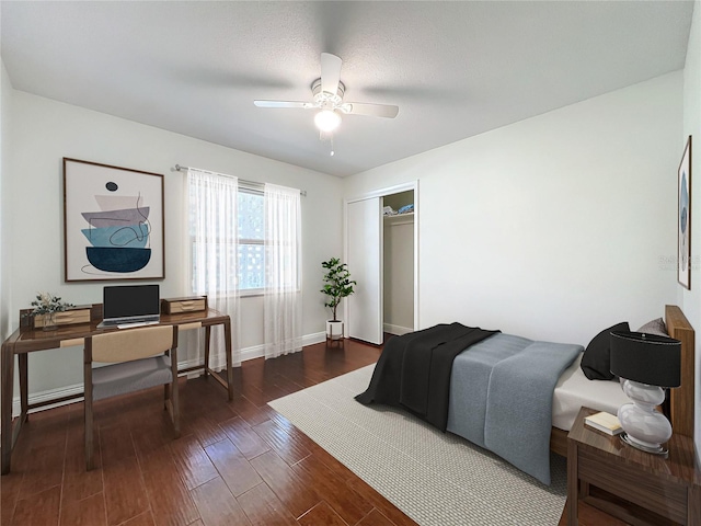 bedroom featuring a textured ceiling, ceiling fan, dark wood-type flooring, and a closet