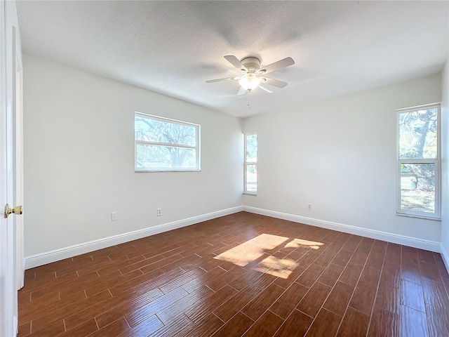 empty room with a textured ceiling, ceiling fan, and dark hardwood / wood-style floors