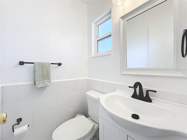 bathroom featuring vanity, toilet, and tile walls