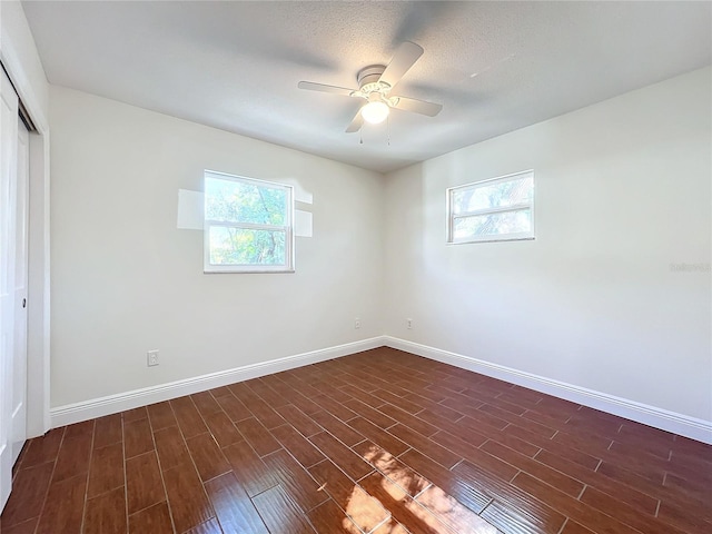 spare room with a textured ceiling, ceiling fan, and dark hardwood / wood-style floors