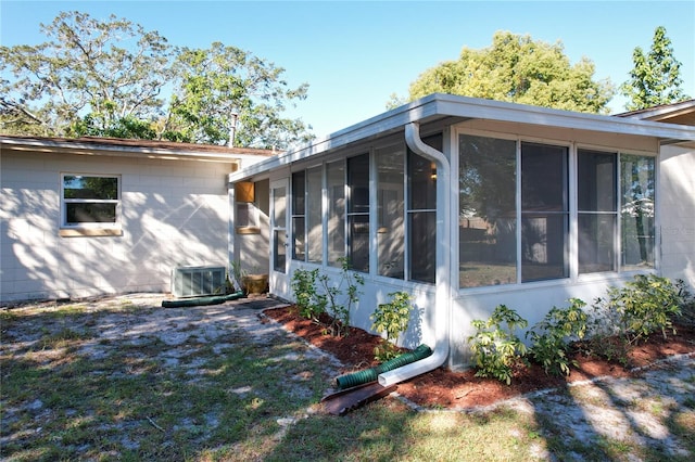 view of property exterior featuring central air condition unit and a sunroom