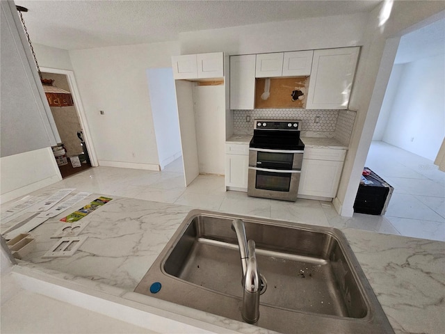 kitchen featuring backsplash, electric stove, sink, and white cabinets