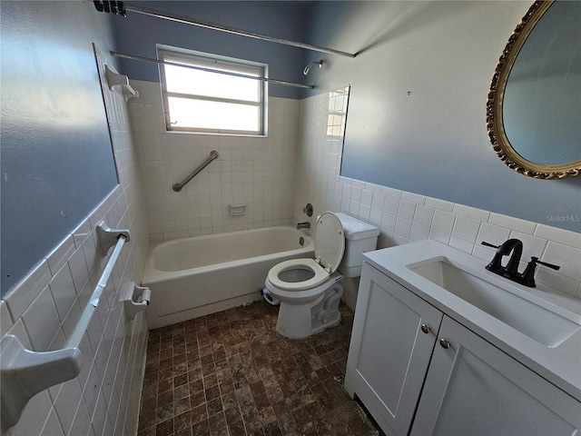 full bathroom with vanity, tiled shower / bath combo, toilet, and tile walls