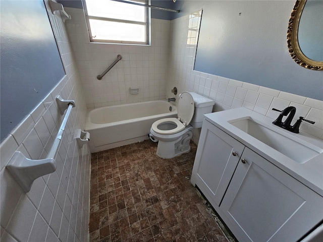 full bathroom featuring tiled shower / bath, vanity, toilet, and tile walls