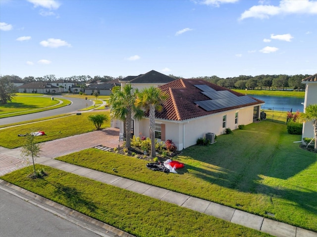 1651 Kingfisher Ct, Kissimmee, FL 34746 - view of side of home with decorative driveway, a tile roof, stucco siding, roof mounted solar panels, and a yard
