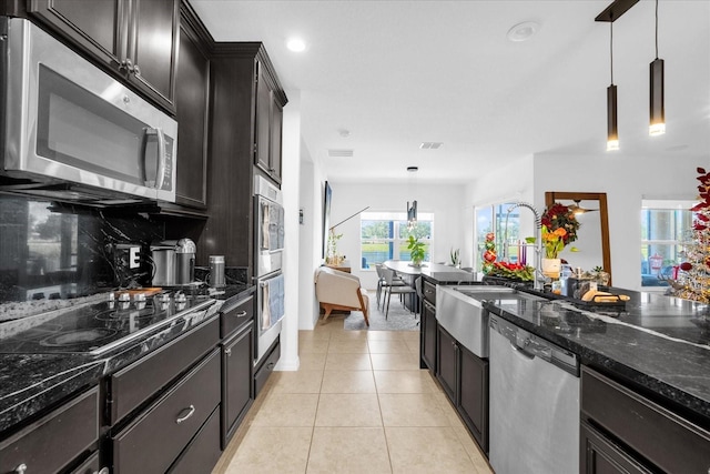 1651 Kingfisher Ct, Kissimmee, FL 34746 - kitchen featuring stainless steel appliances, tasteful backsplash, dark stone counters, light tile patterned flooring, and hanging light fixtures