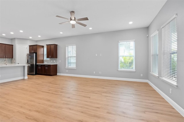 kitchen featuring backsplash, dark brown cabinets, light hardwood / wood-style floors, and stainless steel refrigerator with ice dispenser