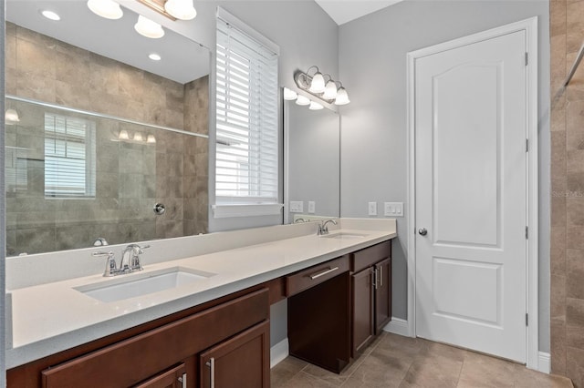 bathroom with a tile shower, vanity, and tile patterned floors