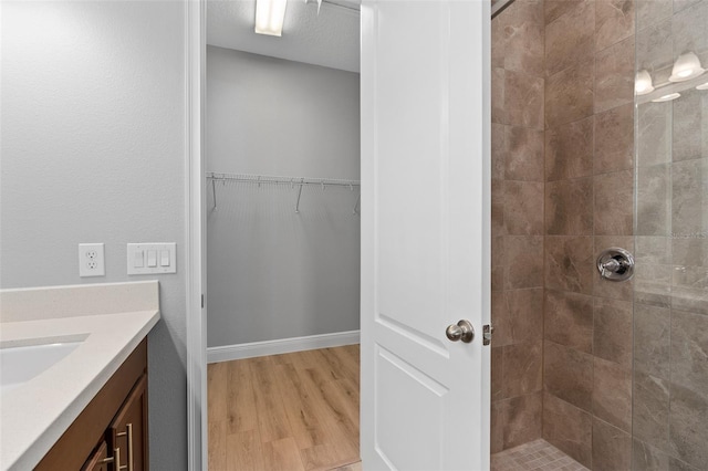 bathroom with tiled shower, vanity, a textured ceiling, and hardwood / wood-style flooring