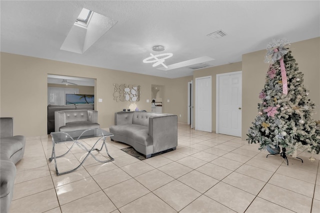 living room with ceiling fan, light tile patterned flooring, and a skylight