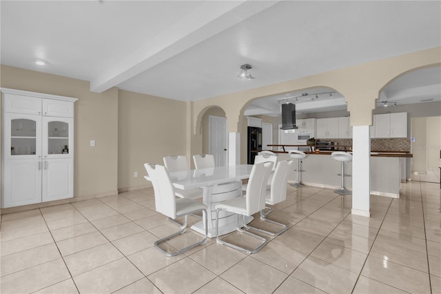 tiled dining space featuring beam ceiling