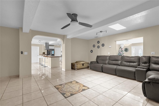 living room with beamed ceiling, light tile patterned floors, and ceiling fan