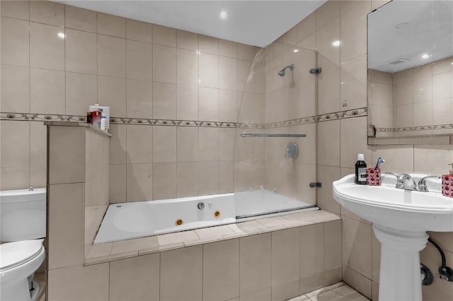 full bathroom featuring tiled shower / bath, toilet, tile walls, and sink