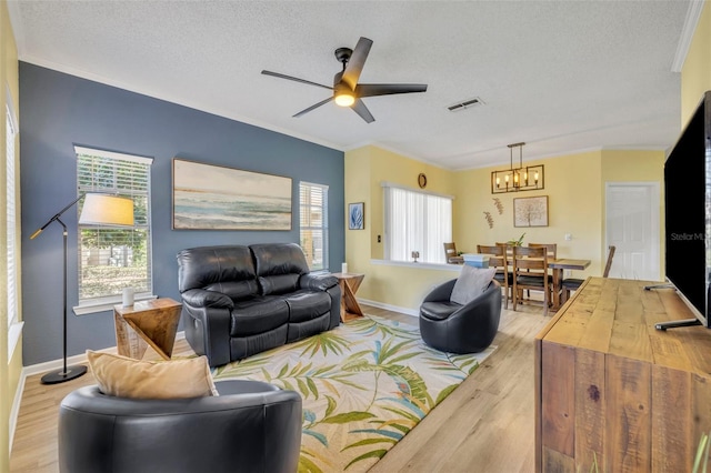 living room with ceiling fan with notable chandelier, light hardwood / wood-style floors, a textured ceiling, and ornamental molding