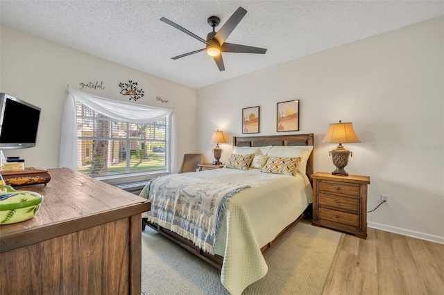 bedroom with ceiling fan, light hardwood / wood-style floors, and a textured ceiling