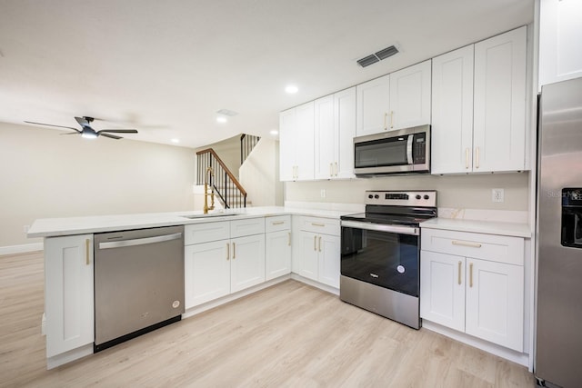 kitchen featuring white cabinetry, ceiling fan, stainless steel appliances, kitchen peninsula, and light hardwood / wood-style floors