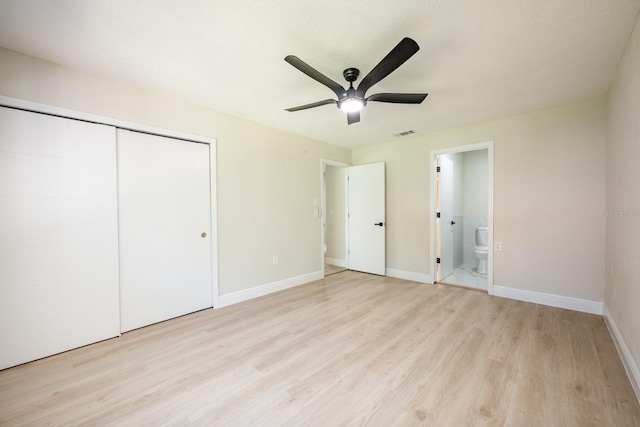 unfurnished bedroom featuring a closet, ensuite bathroom, ceiling fan, and light hardwood / wood-style floors