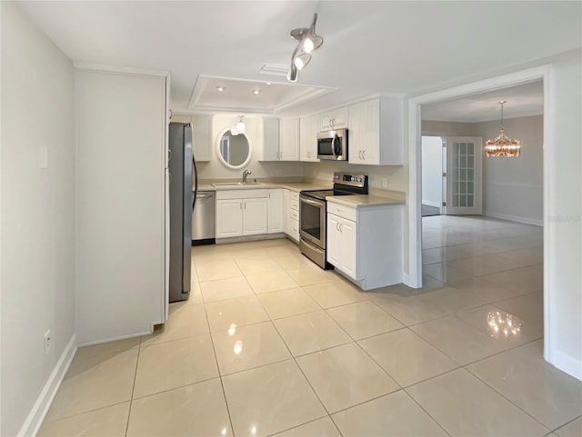 kitchen featuring stainless steel appliances, a tray ceiling, sink, decorative light fixtures, and white cabinets