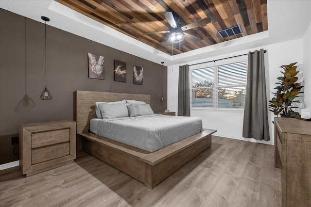 bedroom featuring ceiling fan, a raised ceiling, and light wood-type flooring