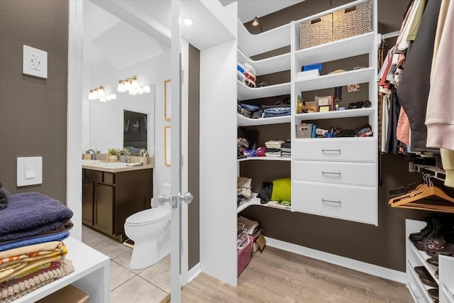 spacious closet with light hardwood / wood-style floors and sink