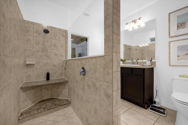 bathroom featuring tile patterned flooring, vanity, toilet, and tiled shower