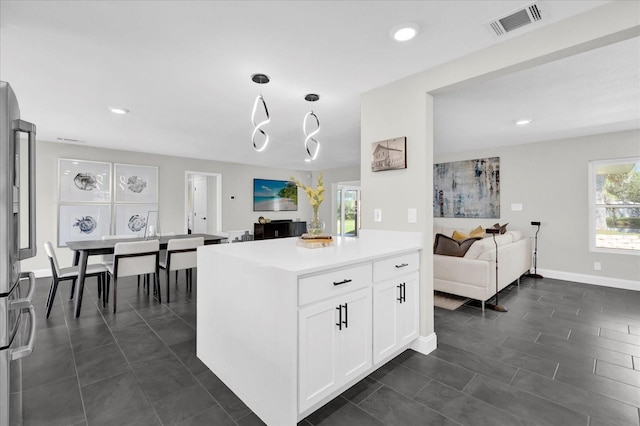 kitchen with white cabinets, pendant lighting, and stainless steel refrigerator