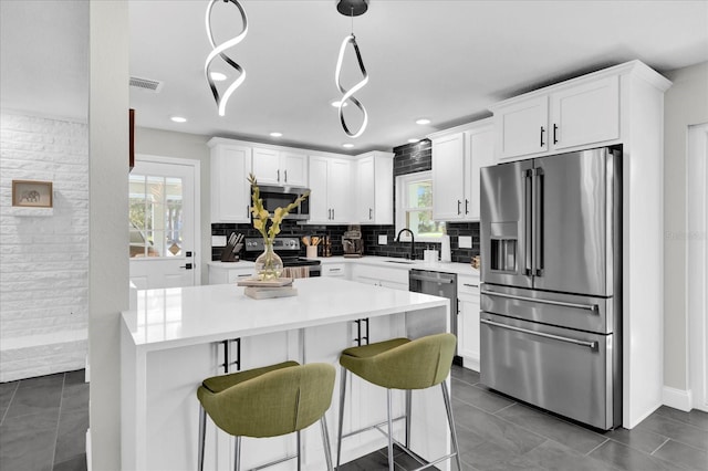 kitchen with white cabinets, appliances with stainless steel finishes, and a healthy amount of sunlight