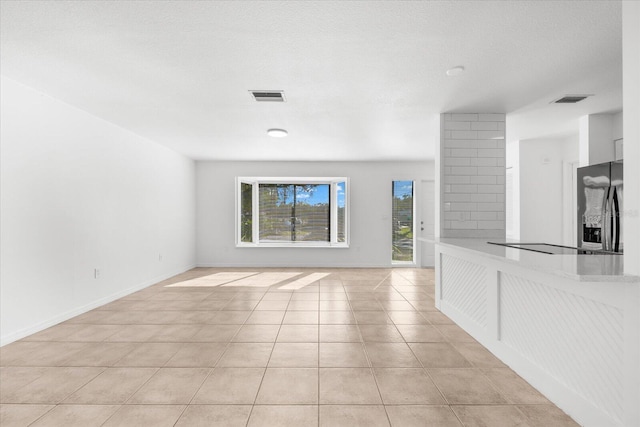 unfurnished living room with a textured ceiling and light tile patterned floors