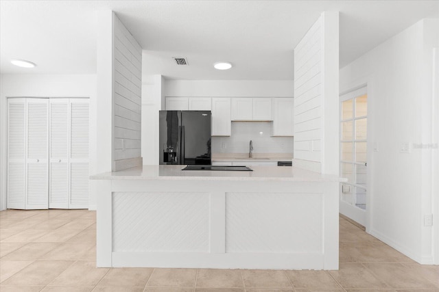 kitchen featuring kitchen peninsula, backsplash, black appliances, white cabinets, and sink