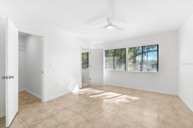 empty room with ceiling fan and light tile patterned floors