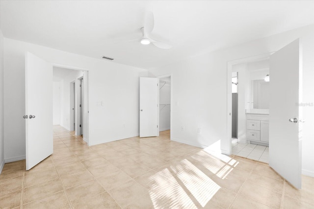 unfurnished bedroom with ceiling fan, ensuite bath, light tile patterned floors, a walk in closet, and a closet