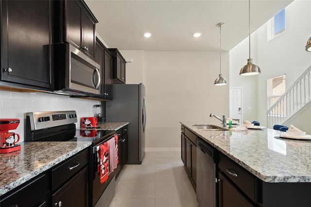 kitchen featuring sink, hanging light fixtures, stainless steel appliances, backsplash, and an island with sink