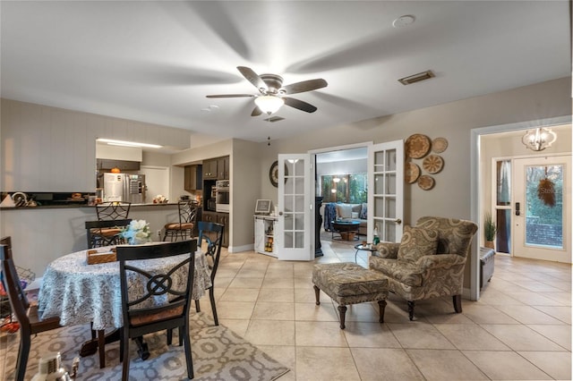 tiled dining room with french doors and ceiling fan with notable chandelier