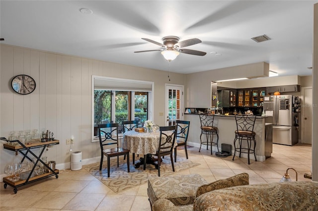 tiled dining room with ceiling fan and wooden walls