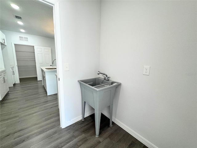 washroom featuring baseboards, dark wood-type flooring, visible vents, and a sink