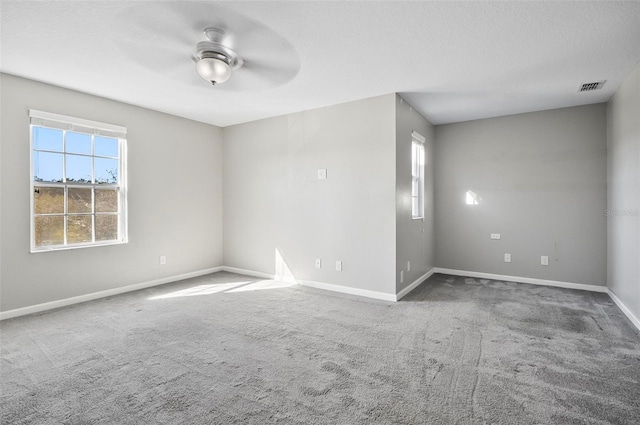 carpeted empty room with a wealth of natural light and ceiling fan