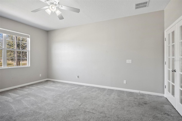 carpeted spare room featuring french doors, ceiling fan, and a textured ceiling