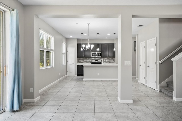 kitchen with stainless steel appliances, light tile patterned flooring, backsplash, a chandelier, and pendant lighting