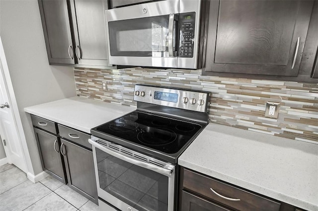 kitchen with appliances with stainless steel finishes, tasteful backsplash, light tile patterned floors, and dark brown cabinets