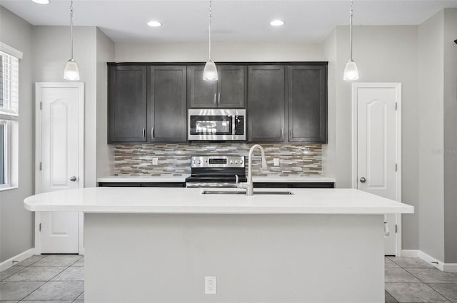 kitchen featuring hanging light fixtures, an island with sink, appliances with stainless steel finishes, and sink