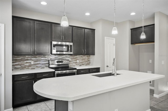 kitchen with a center island with sink, decorative light fixtures, sink, and appliances with stainless steel finishes