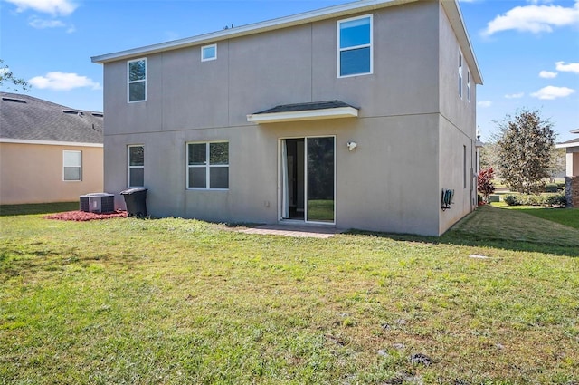 rear view of property with central AC unit and a lawn