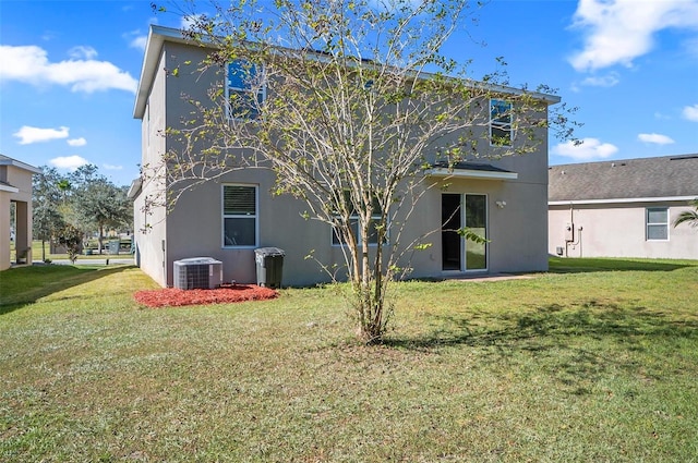 back of property with central air condition unit and a yard