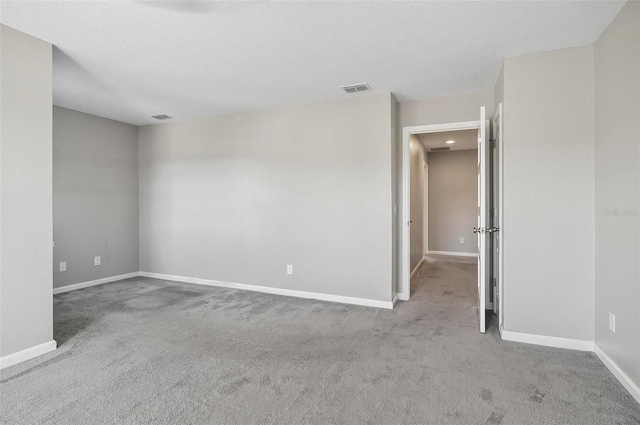 unfurnished room featuring a textured ceiling and light colored carpet