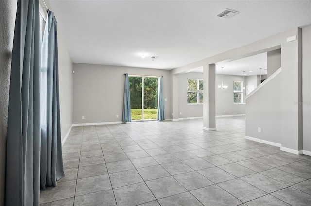 tiled spare room with a notable chandelier